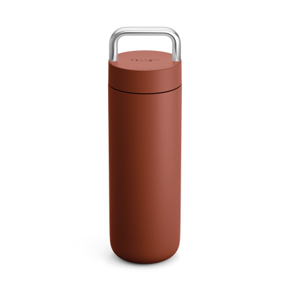 The Fellow Carter Carry Travel Mug is matte brown with a silver handle on the lid, upright position.